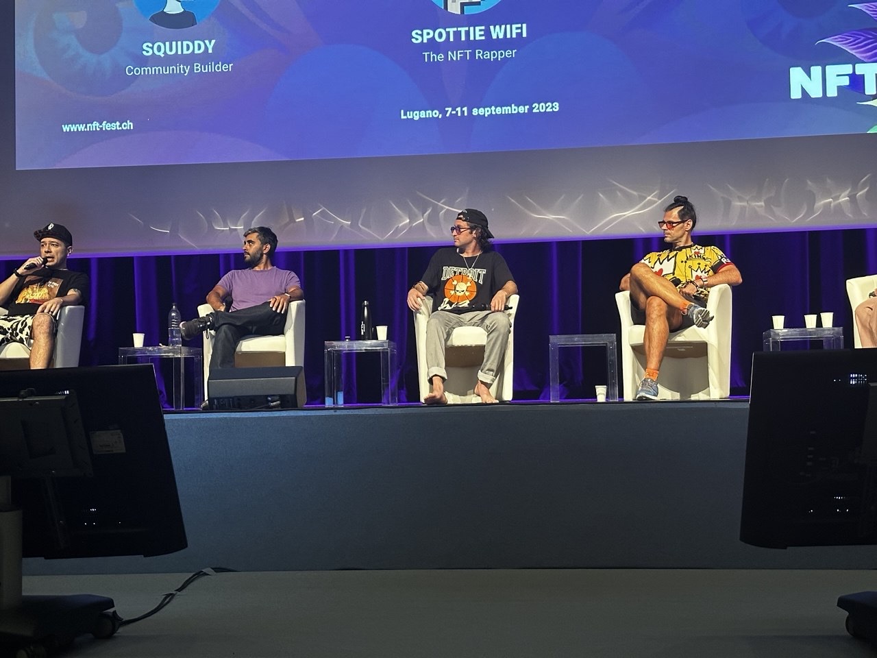 Панель на сцене NFT Fest Lugano, на экране участники Squiddy и Spottie WiFi